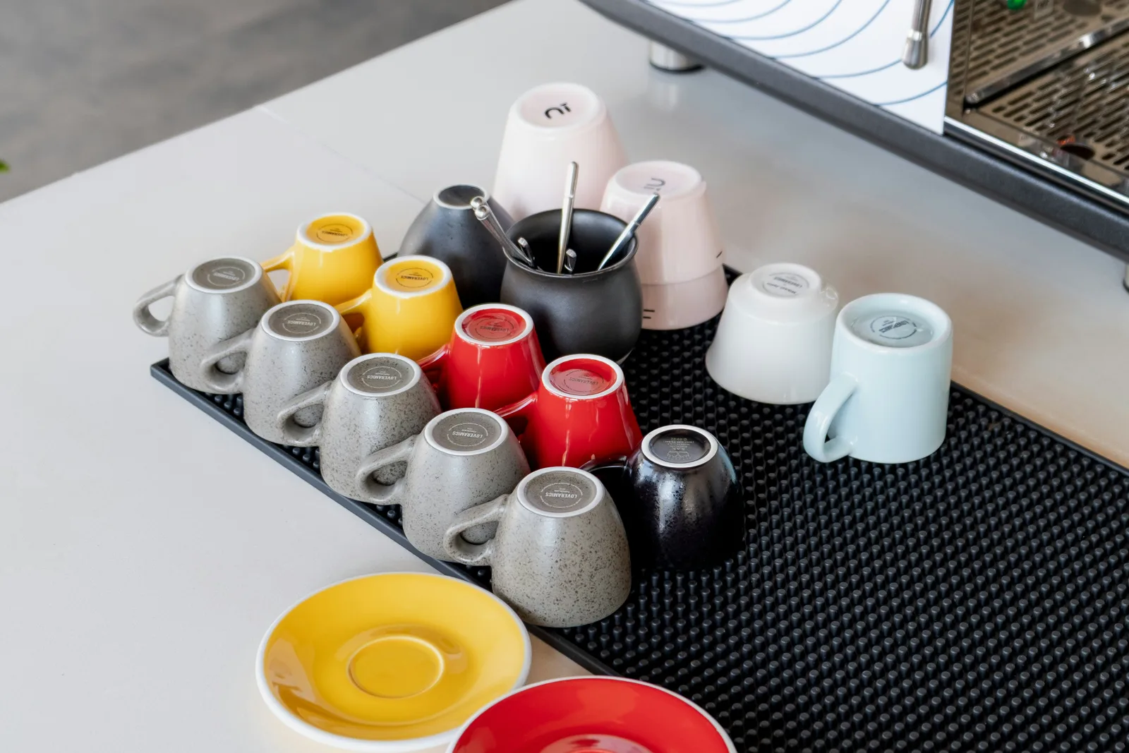 Colorful coffee cups arranged beside an espresso machine
